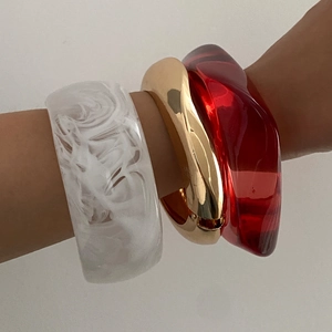 Set di tre bracciali rigidi in resina marmorizzata, metallo dorato e acrilico rosso