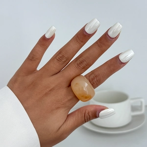 Nahaufnahme eines dicken, bernsteinfarbenen Harzrings mit glänzendem Finish am Finger