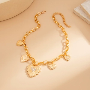 Macro view of gold chain necklace featuring multiple heart pendants with textured finish