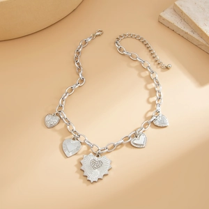 Detail view of multi-pendant heart necklace with textured charms and thick chain