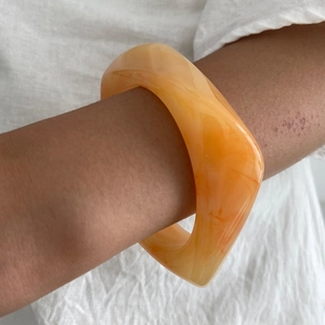 Dettaglio del bracciale in resina ambrata con bordi ondulati e trama sabbia marmorizzata