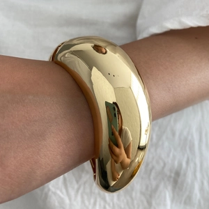 Macro di un bracciale a polsino placcato oro con finitura lucida a specchio per donna