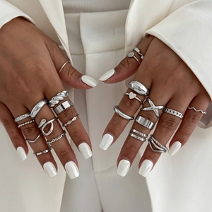 Gros plan de bagues empilables en argent aux motifs croisés et géométriques sur mains