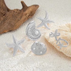 6-piece silver starfish and seashell ring set with pearls on coral and wood background