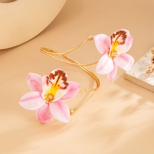 Detailopname van een gouden spiraalvormige orchidee-armband met roze bloemblaadjes