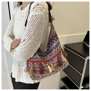 Dettaglio della borsa hobo con motivi geometrici intrecciati, nappe etniche e tracolla
