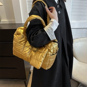 Détail d'un sac à bandoulière matelassé doré avec surpiqûres carrées et fini métallique
