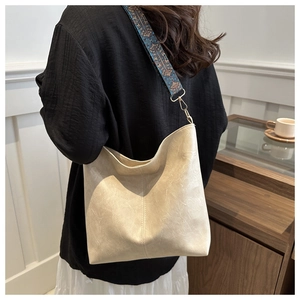 Detailed view of the cream tote bag with an ethnic-style woven shoulder strap worn by model