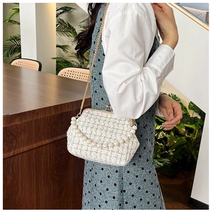 Close-up of white tweed crossbody bag with pearl handle and golden chain strap detail