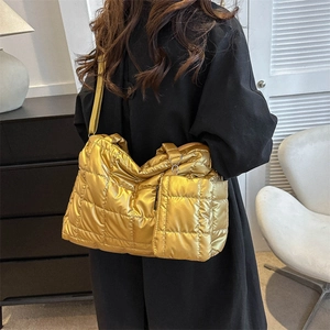 Sac fourre-tout matelassé doré métallisé avec pochette porté à l'épaule en studio