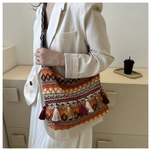 Dettaglio di borsa tote boho con nappe colorate e motivi geometrici intrecciati