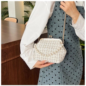 Detail of tweed shell bag featuring a pearl handle, gold chain, and retro clasp closure