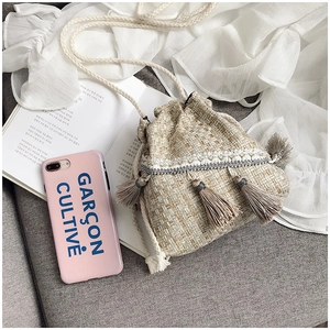 Dettaglio macro di borsa a secchiello intrecciata con perle, paillettes e lunghe nappe