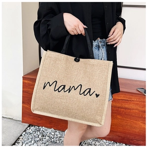 Detail of linen tote bag featuring black Mama script and heart print with button closure