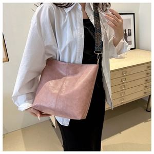 Detail of pink faux leather tote bag featuring a wide geometric jacquard shoulder strap