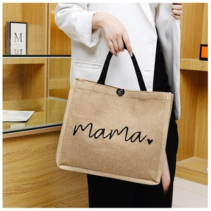 Detail of jute tote bag showing Mama print, black handles and button closure