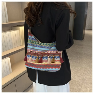 Dettaglio ravvicinato della borsa etnica intrecciata con onde geometriche e nappe vivaci