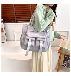 Vue détaillée d'un sac en nylon gris avec poches à rabat et boucles blanches réglables