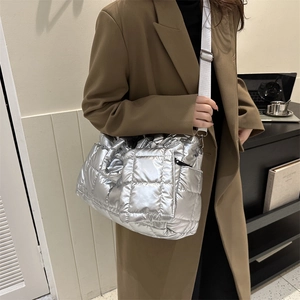 Détail du sac matelassé métallisé avec large bandoulière porté par un mannequin en manteau