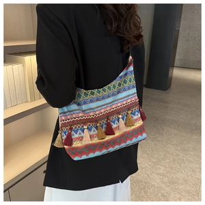 Dettaglio borsa boho in tessuto con motivi geometrici a onde e nappe colorate