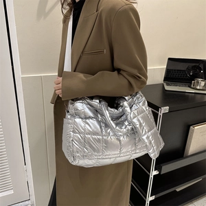 Gros plan du sac cabas matelassé argenté porté avec un blazer marron oversize