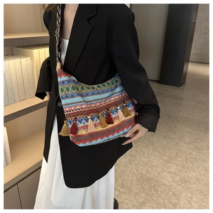 Dettaglio borsa a tracolla etnica con frange colorate e motivi geometrici intrecciati