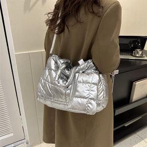Grand sac cabas matelassé argenté porté par un mannequin pour un style d'épaule chic