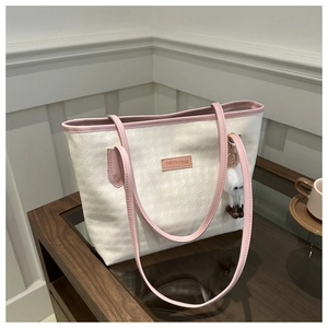 Dettaglio della borsa tote beige pied-de-poule con bordo rosa e ciondolo a pompon