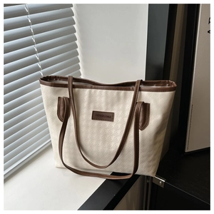 Dettaglio macro della trama pied de poule e finiture in pelle marrone della borsa tote