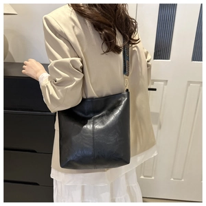 Detailed view of black leather tote bag with vintage patterned wide jacquard strap