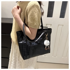 Dettaglio della borsa tote nera pied-de-poule con ciondolo decorativo a pompon bianco