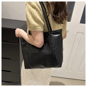 Primo piano della trama pied-de-poule di una grande borsa tote nera indossata