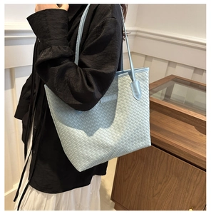 Détail du sac cabas tressé bleu clair avec texture fine et empiècement cuir à l'épaule