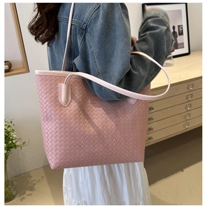 Sac fourre-tout tissé rose porté à l'épaule par un mannequin avec logo de mode
