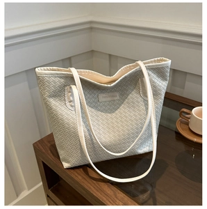 Détail d'un sac cabas tressé blanc avec étiquette FASHION & BAGS sur un meuble