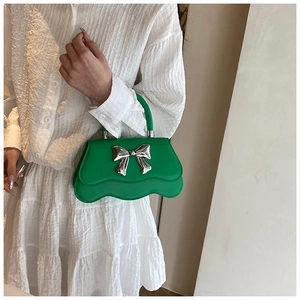 Détails du bord festonné et du nœud argenté sur un sac à main en cuir vert vif