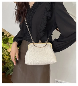 Detail of white woven shell bag with gold curved metal handle and chain shoulder strap