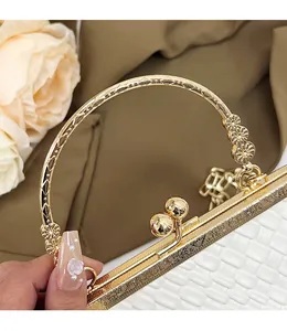 Detail of white woven shell bag with gold engraved floral handle and double ball clasp