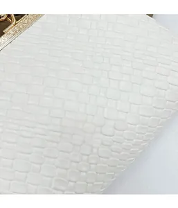 Detailed macro view of white woven texture and vintage gold engraved clasp on shell bag