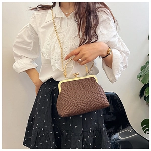 Detail of brown checkered woven shell bag with golden metal handle and chain strap