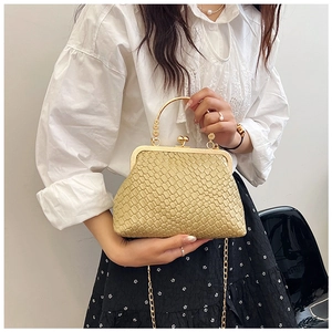 Detailed texture of champagne gold woven shell bag with floral metal handle and chain