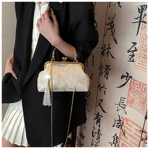 Detail of floral embroidery on silk handbag with metal handle and green tassel