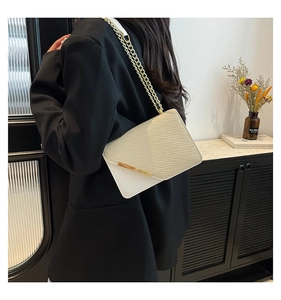 Detail of off-white shoulder bag with twill weave texture and gold metal chain strap