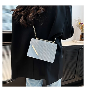 Detailed view of blue crossbody bag with gold chain strap and textured fabric panels