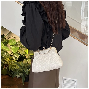 Detail of white woven shell bag with gold metal handle and luxury chain strap