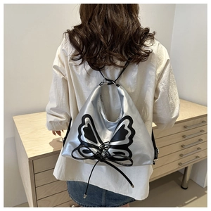 Sac à dos argenté avec applique papillon noire et nœud porté par un mannequin