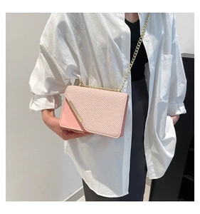 Pink crossbody bag with diagonal quilted texture and gold chain strap shown on a model
