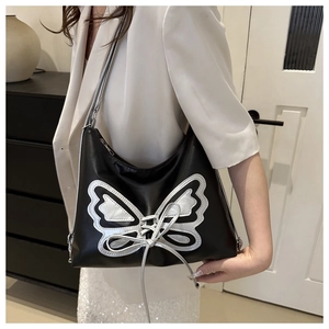Détail du sac bandoulière en cuir noir avec broderie papillon argentée et lanières croisées