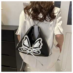 Vue détaillée d'un sac à dos triangulaire noir avec applique papillon argentée et rubans