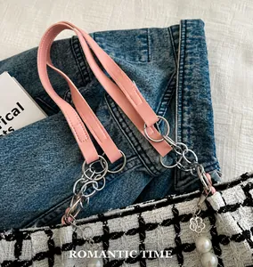Macro detail of plaid tweed tote bag with pink leather handle and pearl chain charm